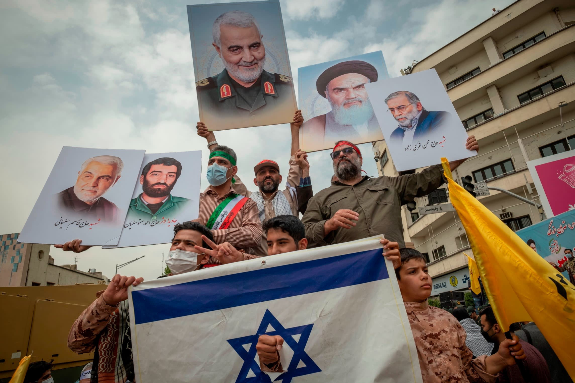 Iranian demonstrators stage a rally behind a torn Israeli flag