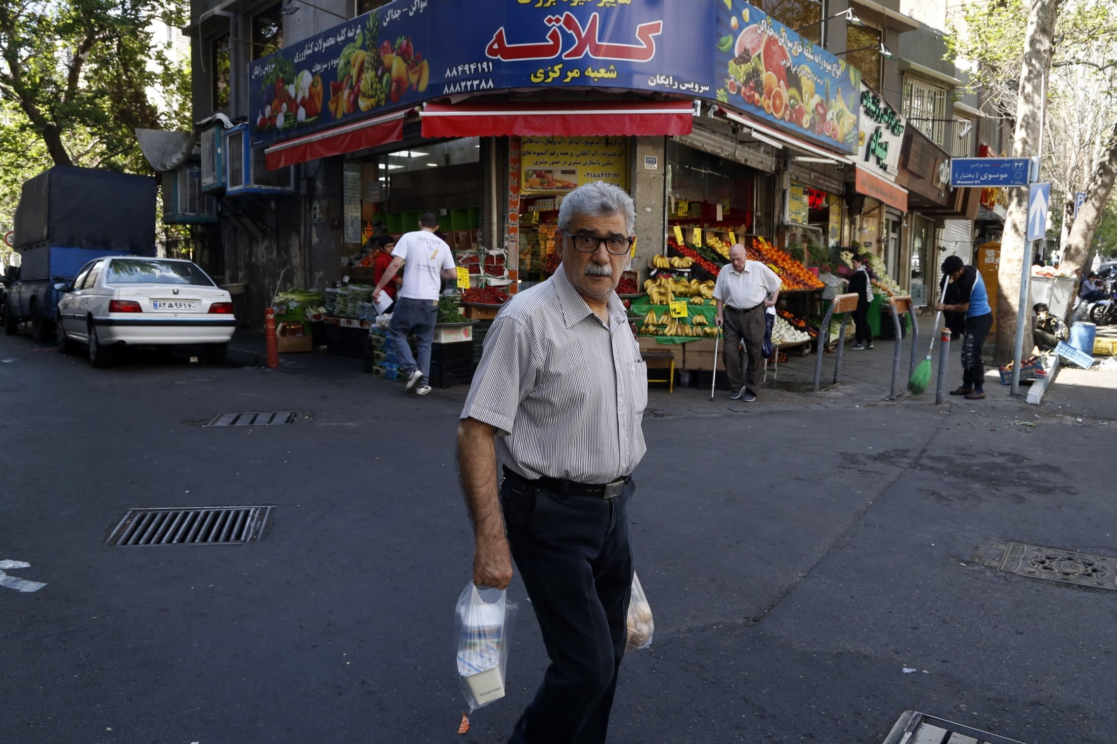 A man carrying shopping bags, with a shop in the background on April 8