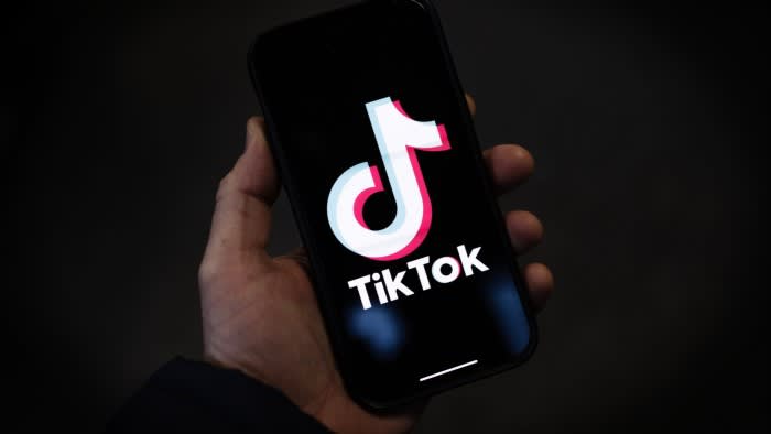 A TikTok logo is displayed on an iPhone
