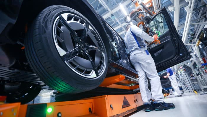 A worker fits the doors for an electric Volkswagen car at a plant in Germany