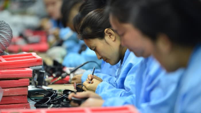 Workers wearing blue uniforms holding circuit board components