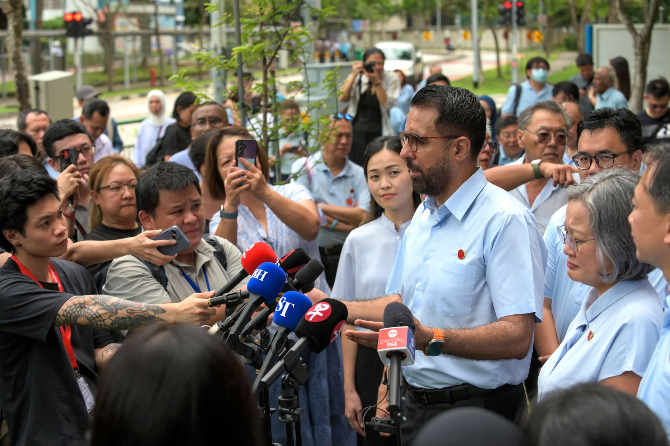 Pritam Singh addresses the media outside Poi Ching School in Singapore, surrounded by journalists and microphones