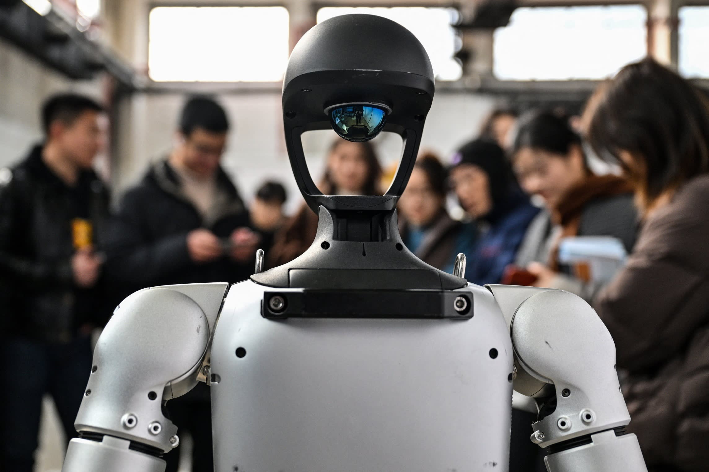 People stand next to a humanoid robot during a conference