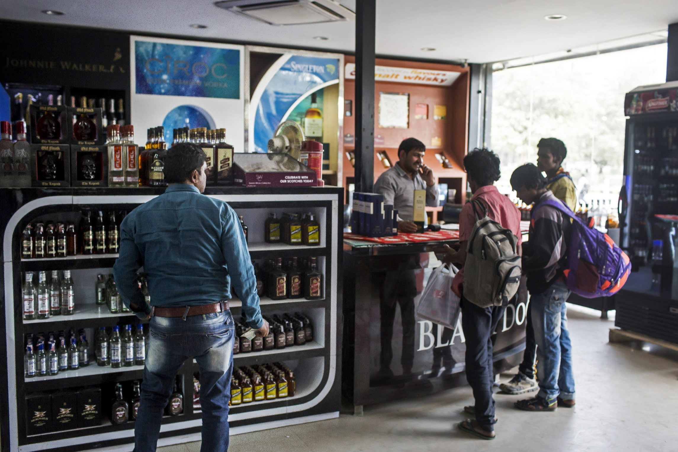 Customers stand inside a roadside liquor store located in Gurgaon, Haryana, India