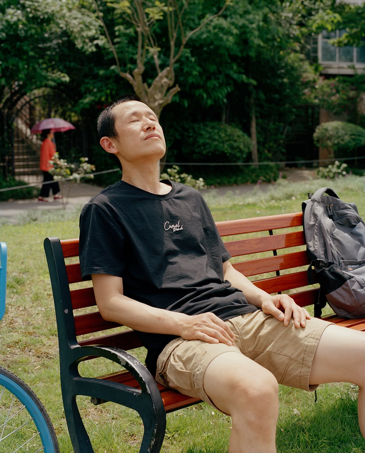 A man relaxes on a park bench with eyes closed