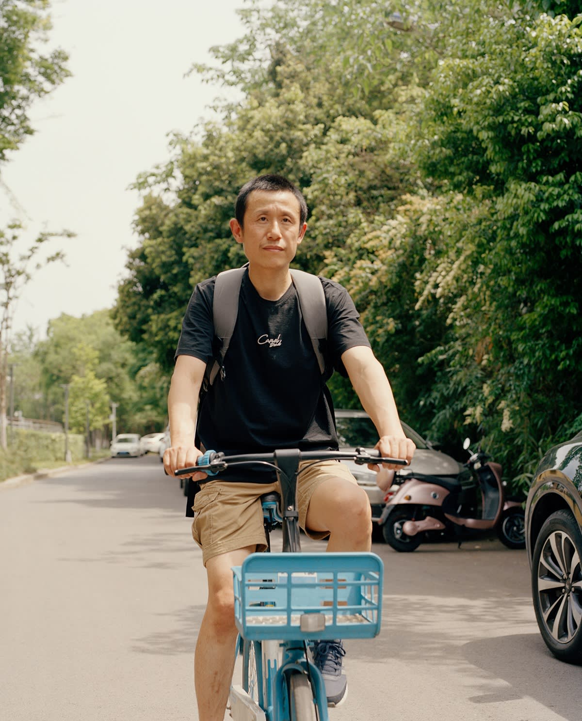 A man rides a blue bicycle on a sunny street