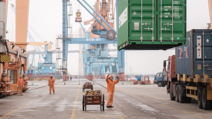 A worker assists while a container is lowered at a port in Haiphong, Vietnam