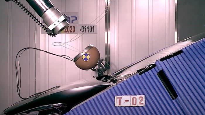 A still from a video of a Japanese car safety test where a rounded object is launched at a car