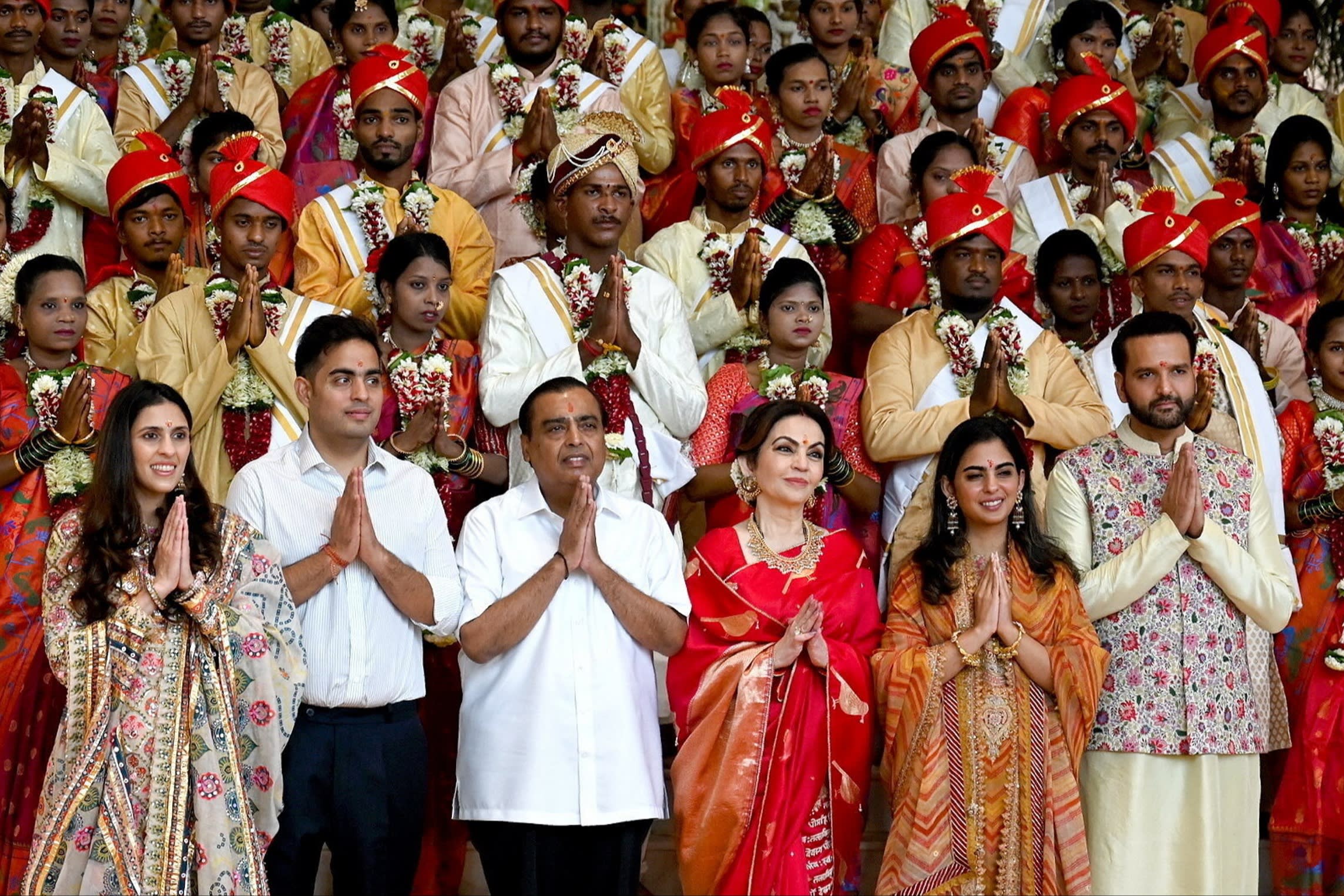 Akash and his wife Shloka, Mukesh and his wife Nita, and Isha and husband Anand Piramal stand in the front row of a mass wedding ceremony for the underprivileged