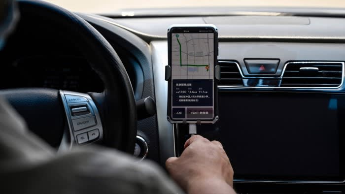 A driver uses the Didi Chuxing ride-hailing app on his smartphone while driving along the street in Beijing