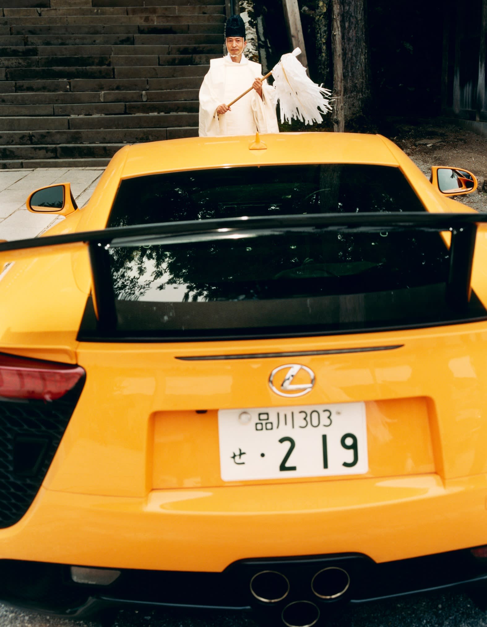 A priest in front of a Lexus LFA outside Suwa Taisha shrine