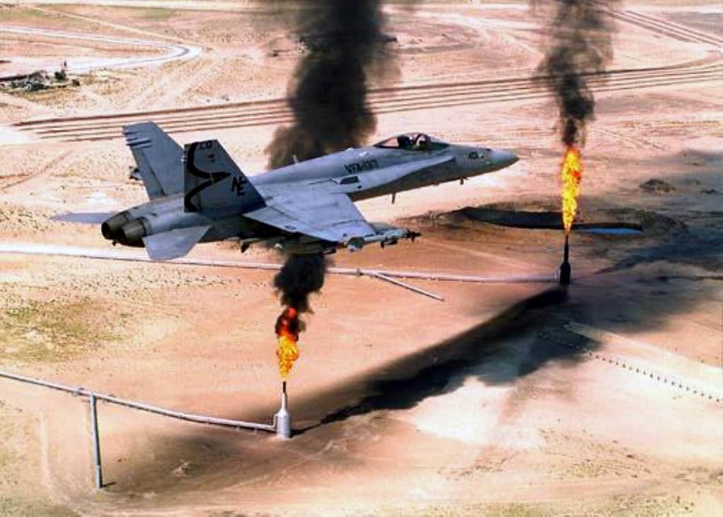A US F-18 fighter jet flies over gas flares at an oil well in northern Kuwait in 1995. Photo: AFP