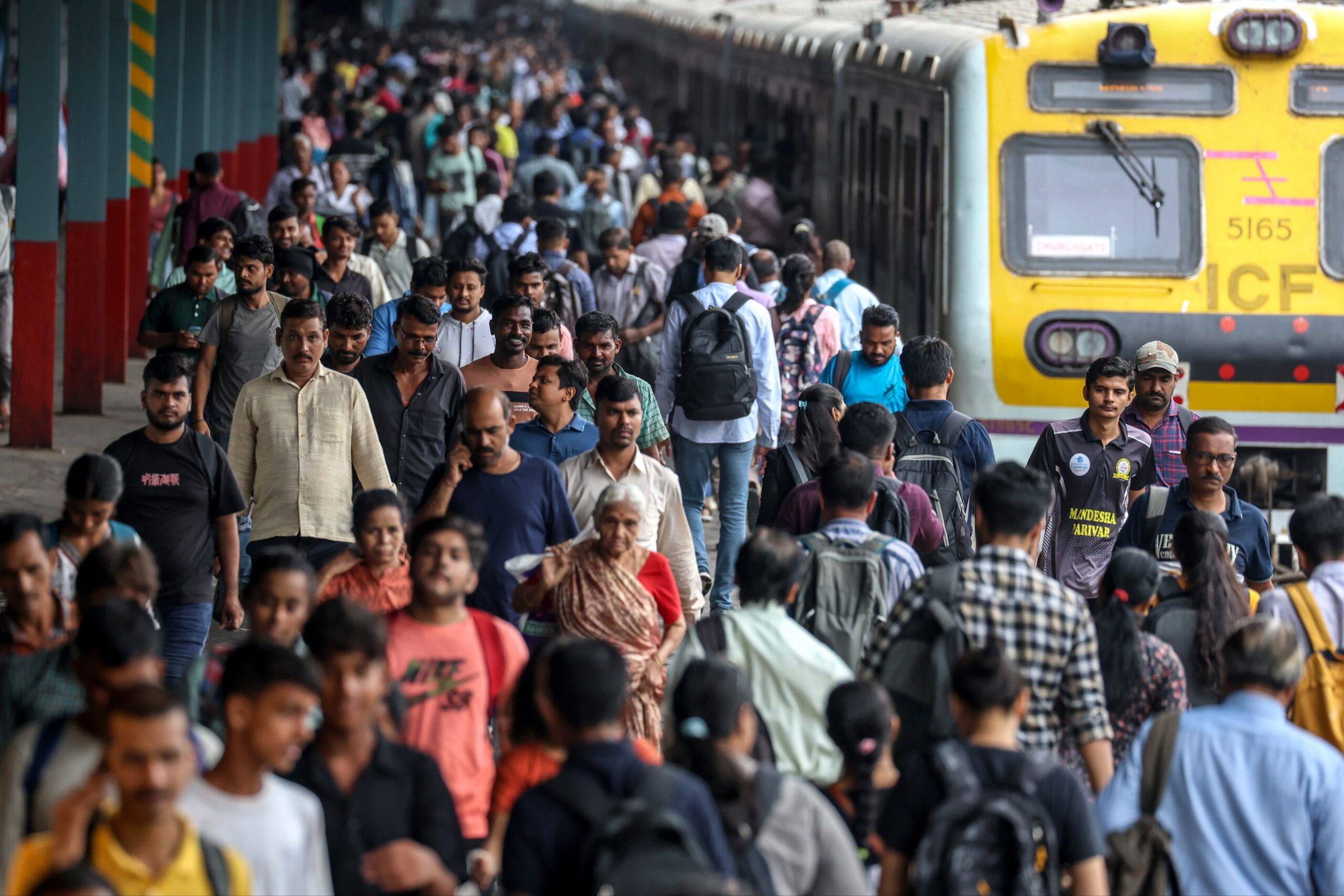 Indian commuters wait for the local train at Borivali railway station in Mumbai