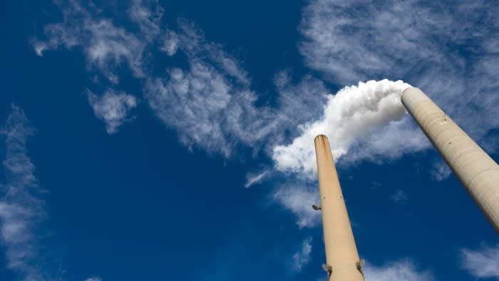 The smoke stacks at a coal plant against a blue sky