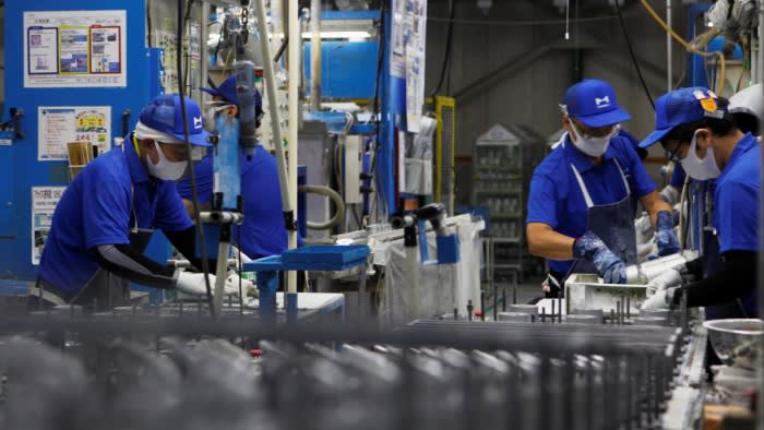 Blue-uniformed workers on an assembly line at a Marelli factory in Japan