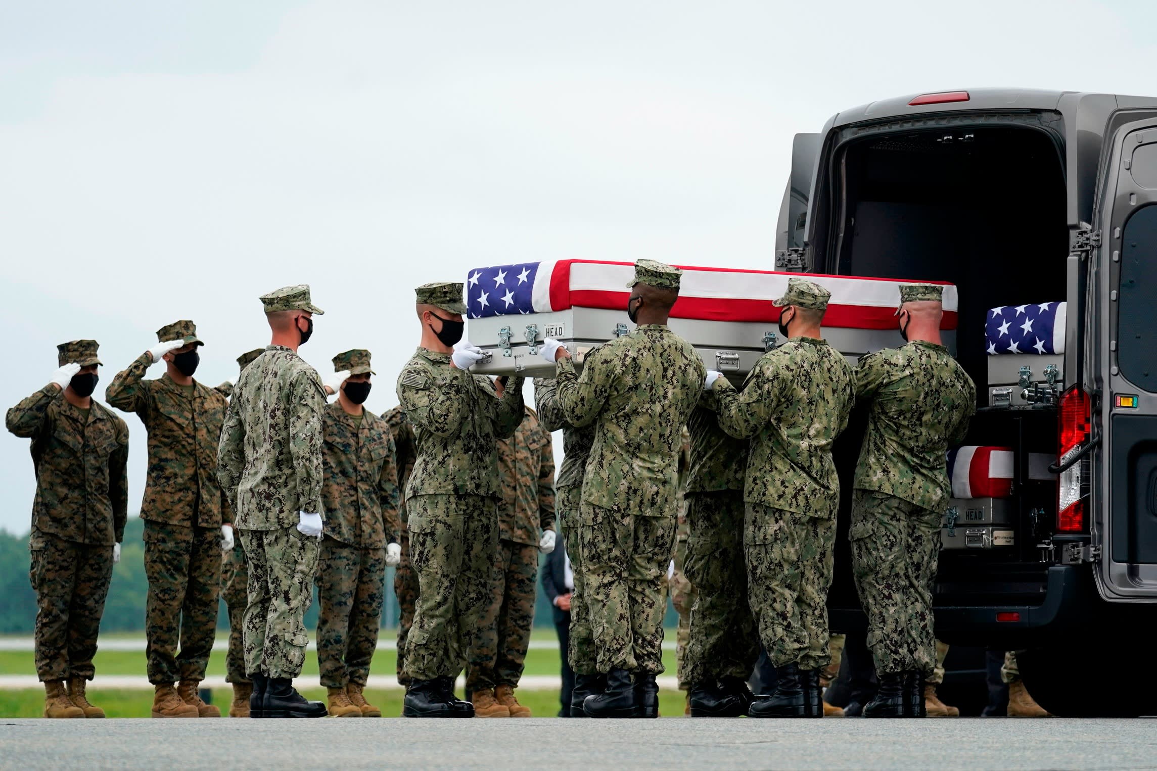 Troops transferring a flag-draped coffin into a vehicle