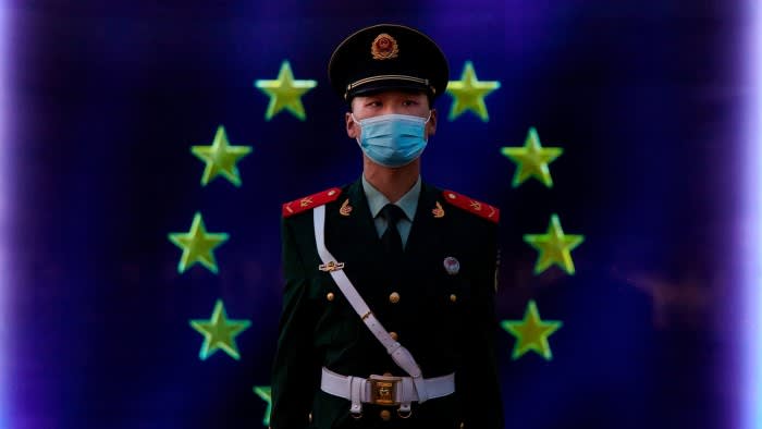 A Chinese police officer stands in front of an EU flag