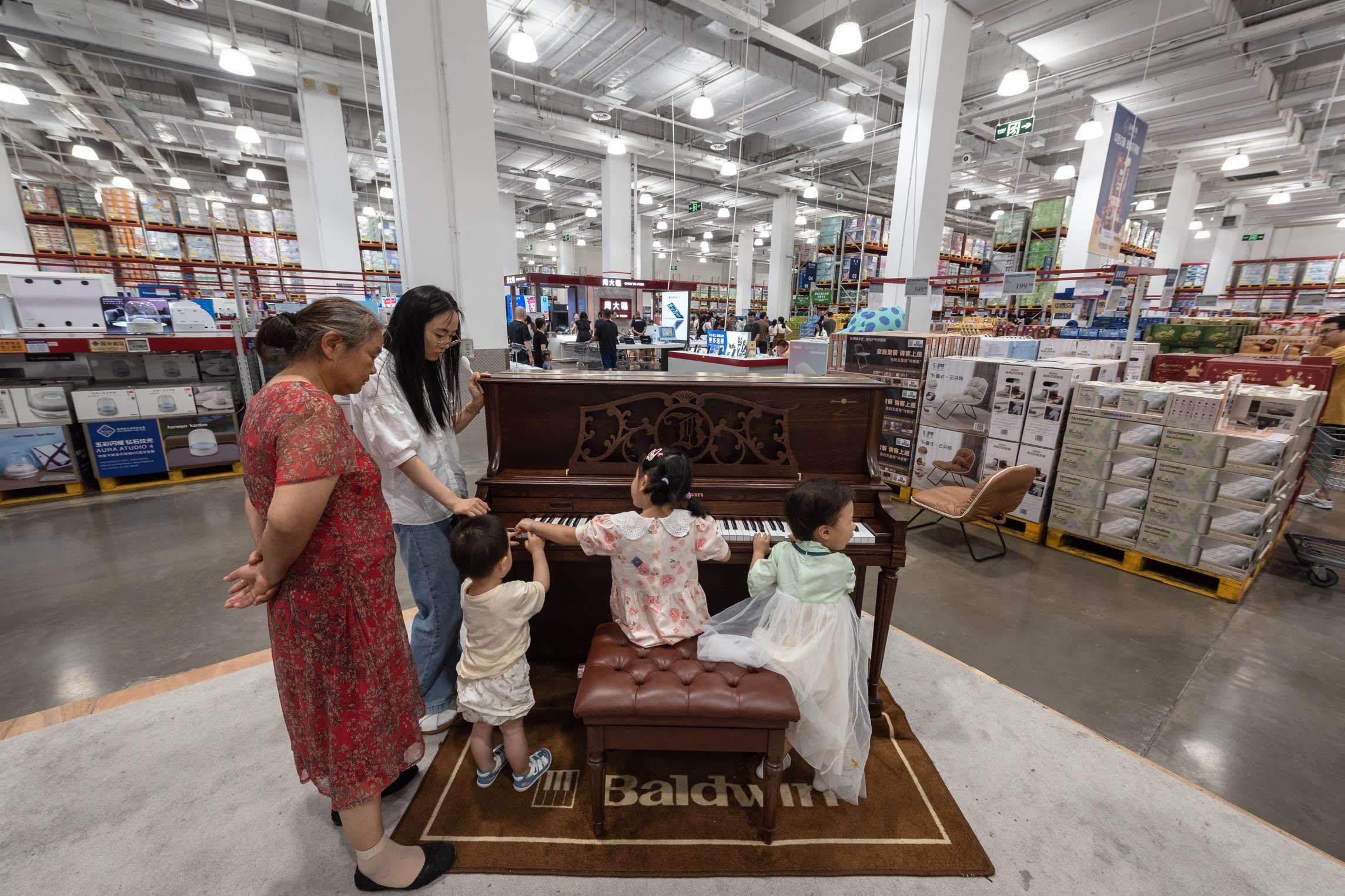 Children play with a piano as adults look on