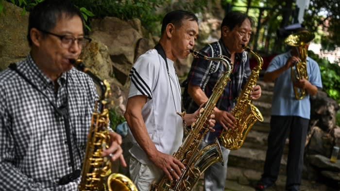 A group of men play brass instruments including saxophones at a park in Shanghai