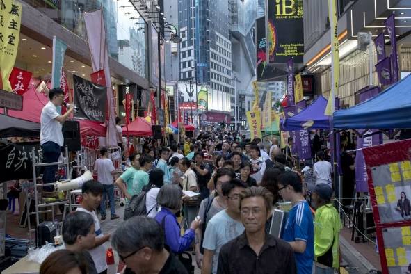 Crowd walking through a busy street market lined with colourful tents and banners