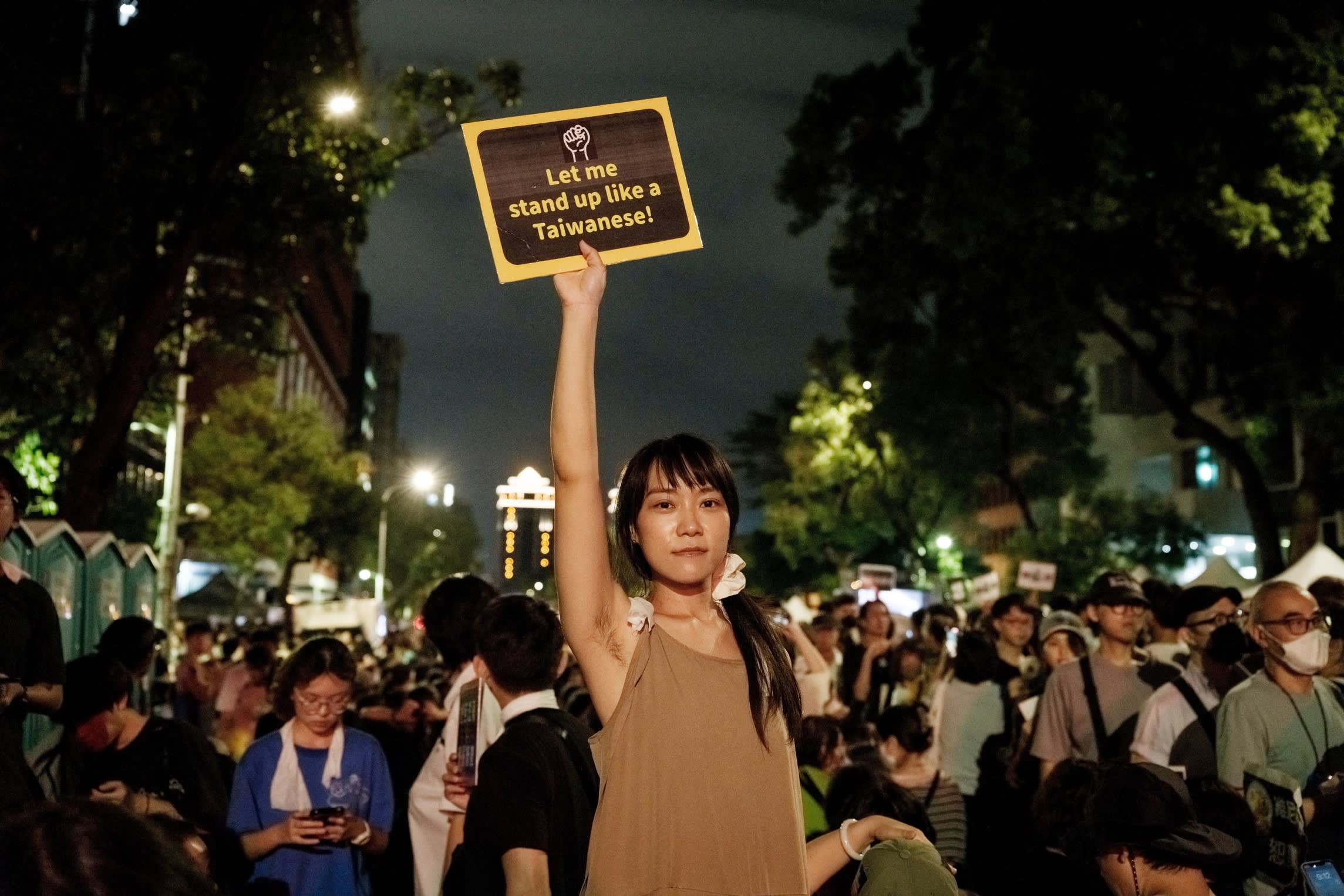 A woman holds a placard that reads ‘Let me stand up like a Taiwanese!’ at a protest in Taipei against a KMT-led move to expand parliamentary powers in May 2024