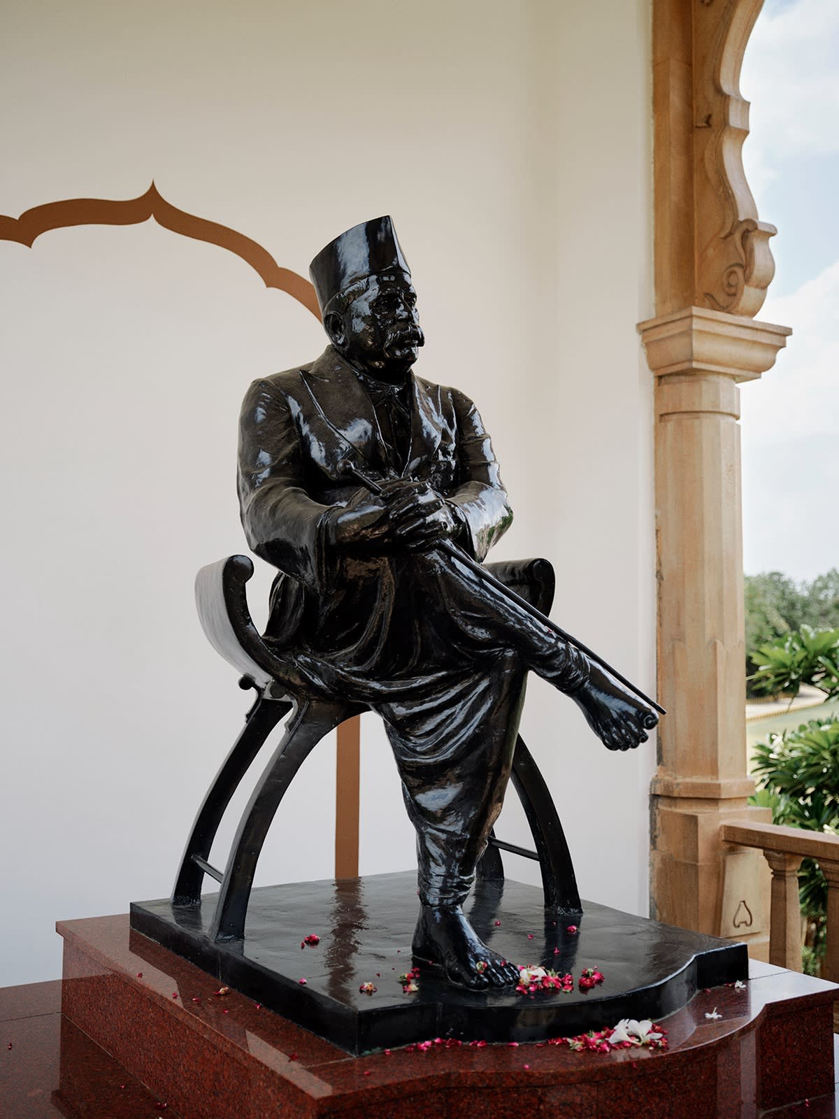 A midsized black statue of a man sitting in a chair