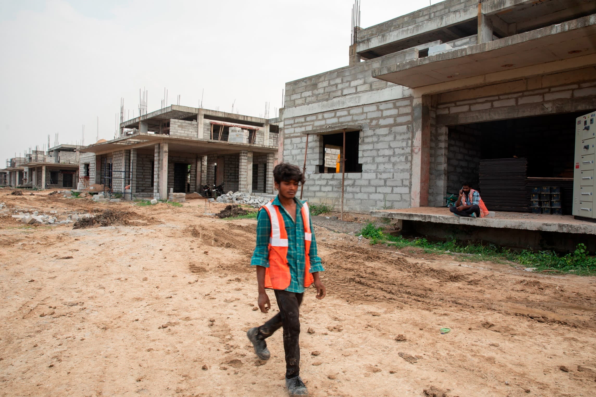 a person walks past uncompleted government employee houses