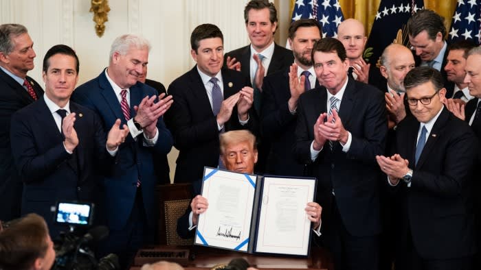 US President Donald Trump, surrounded by lawmakers, displays the signed bill during a signing ceremony for the Genius Act