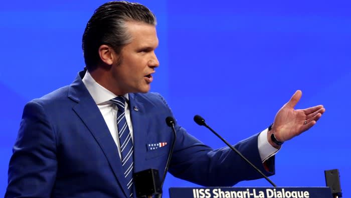 Pete Hegseth speaks at a podium during the IISS Shangri-La Dialogue, gesturing with his left hand as he addresses the audience