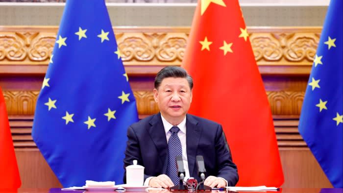 Chinese President Xi Jinping, sitting in front of a row of the EU and Chinese flags