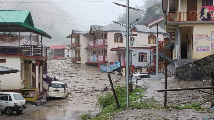 Muddy water runs past residential buildings following a mudslide in India’s Uttarakhand state