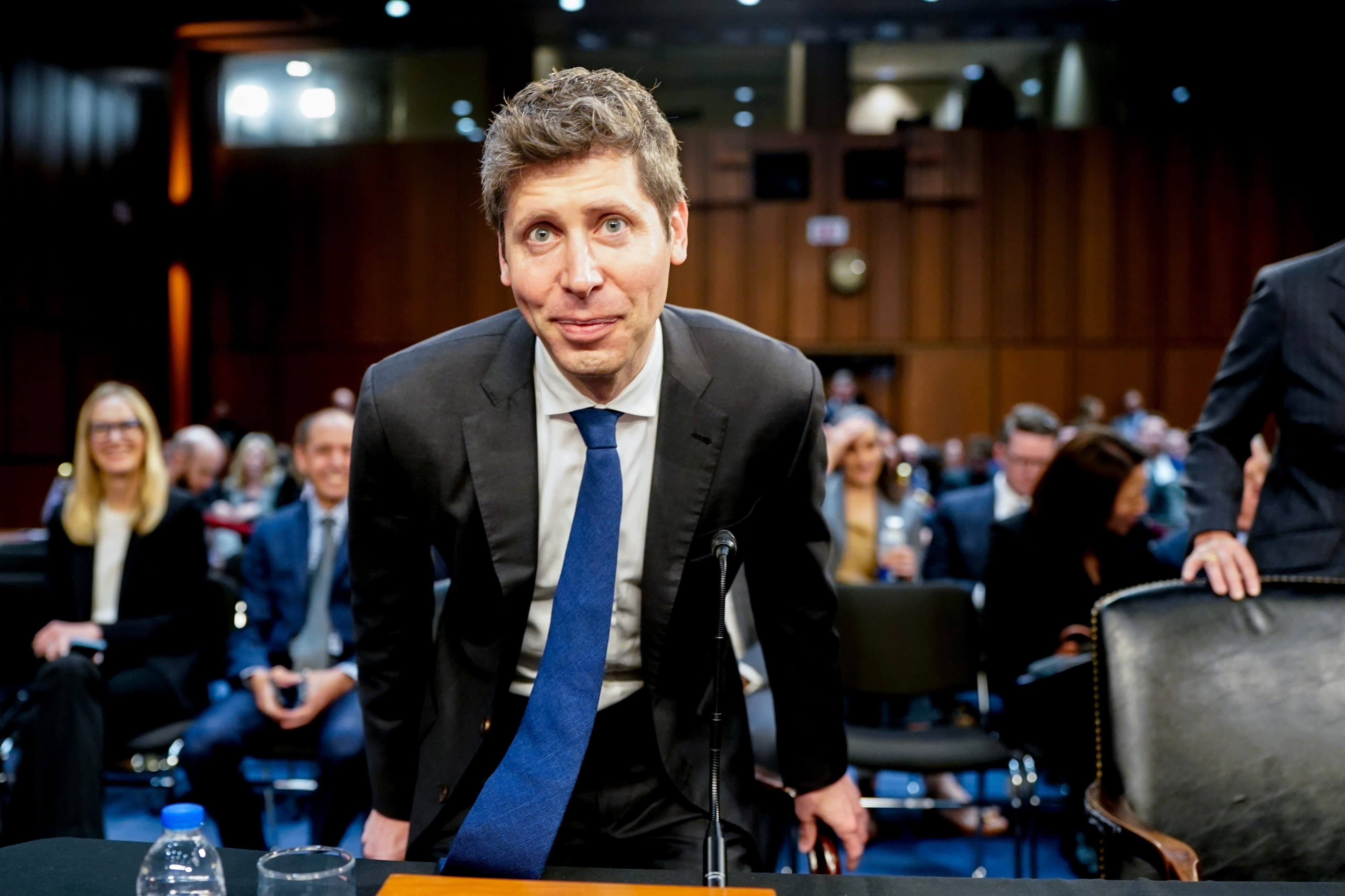 OpenAI chief Sam Altman leans forward at a US Senate committee hearing in May, with people seated and watching in the background.