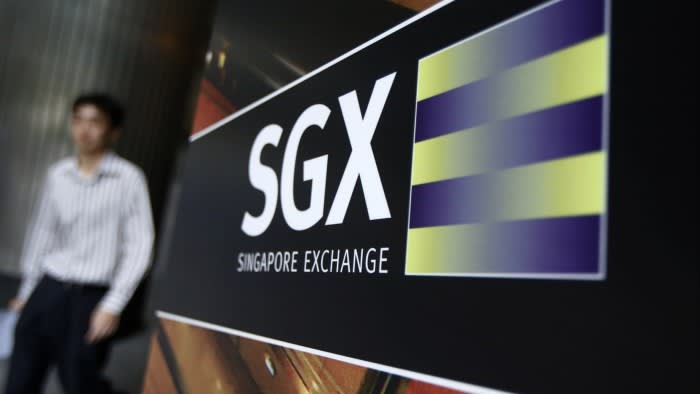 A person walks past a large sign of the Singapore Stock Exchange prominently displayed outside its premises.