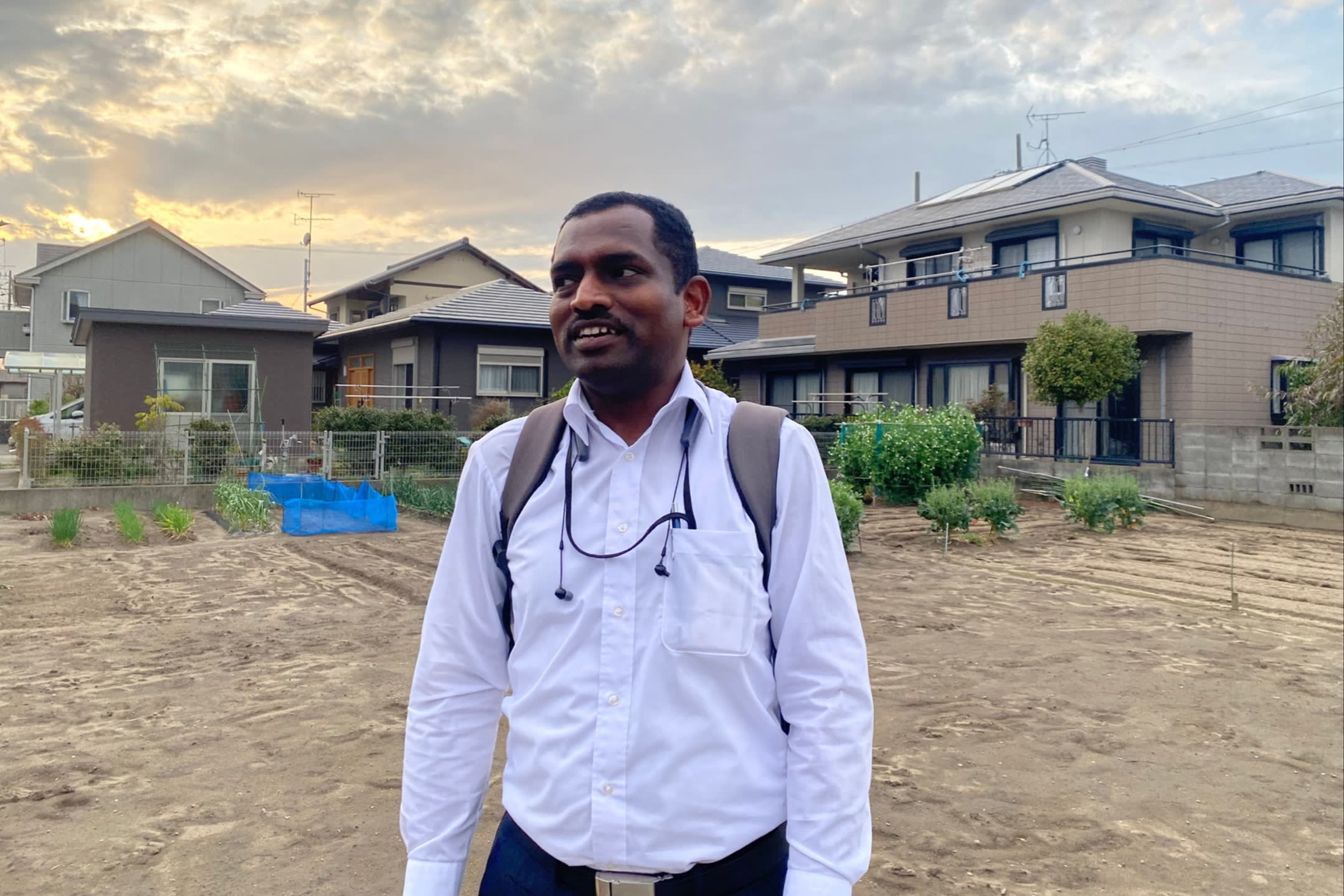 Sundararaj Muthu Selvan stands outdoors in front of residential houses in Hamamatsu
