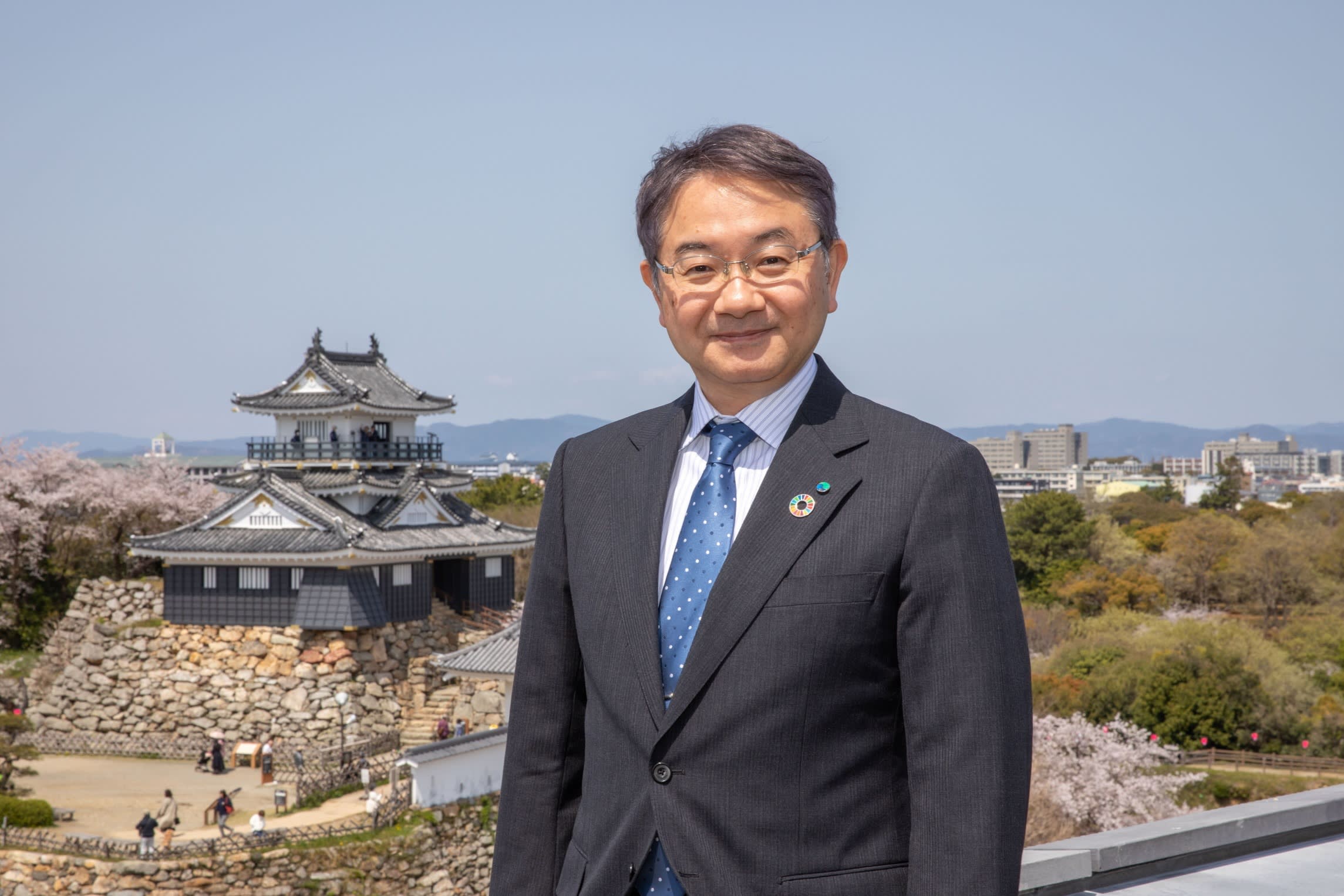 Yusuke Nakano with Hamamatsu Castle and cherry blossoms in the background.