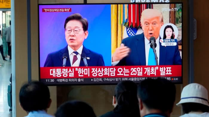 People watch a TV news broadcast showing images of of South Korean President Lee Jae Myung and US President Donald Trump