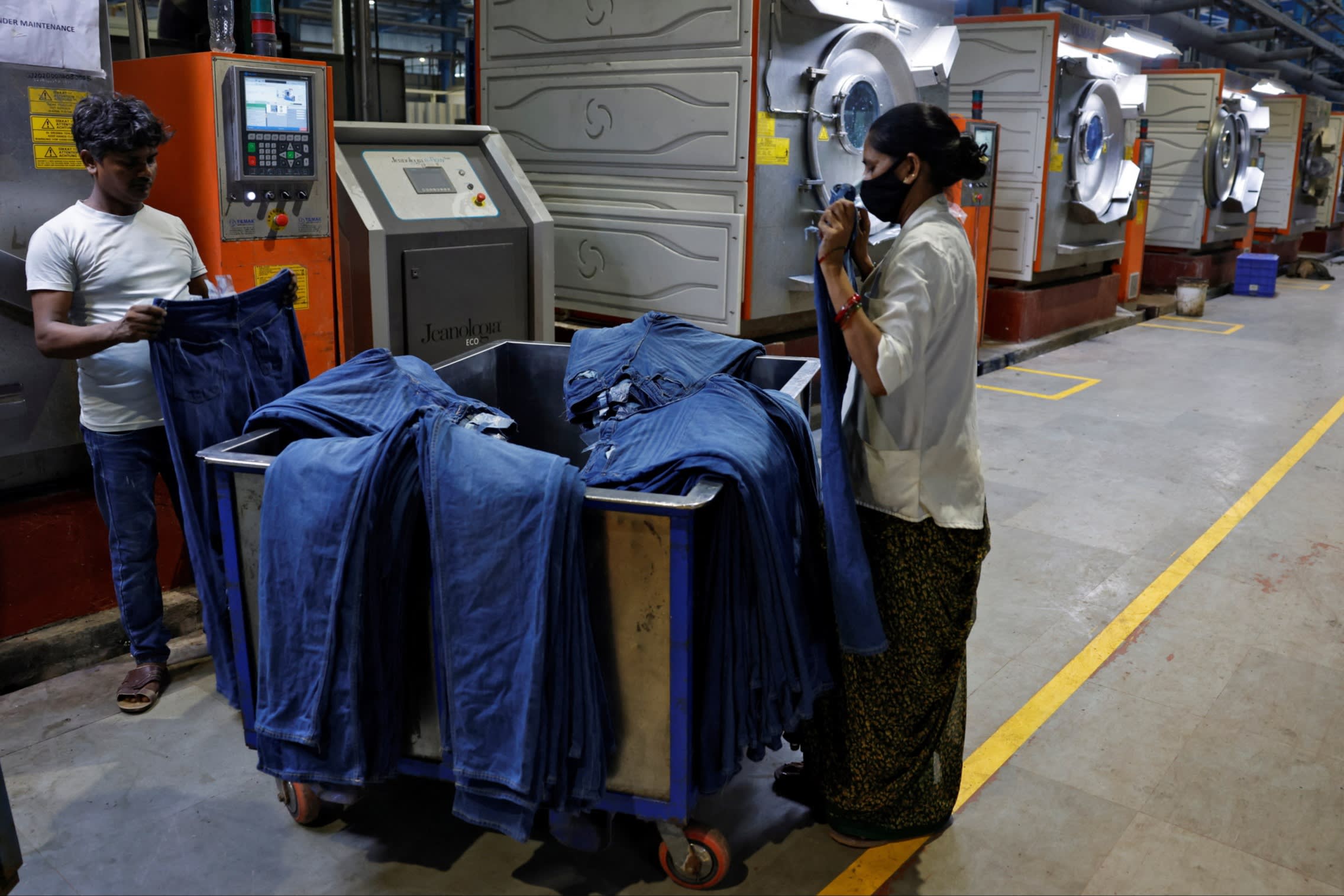 Workers examine washed jeans at an Indian clothing plant 