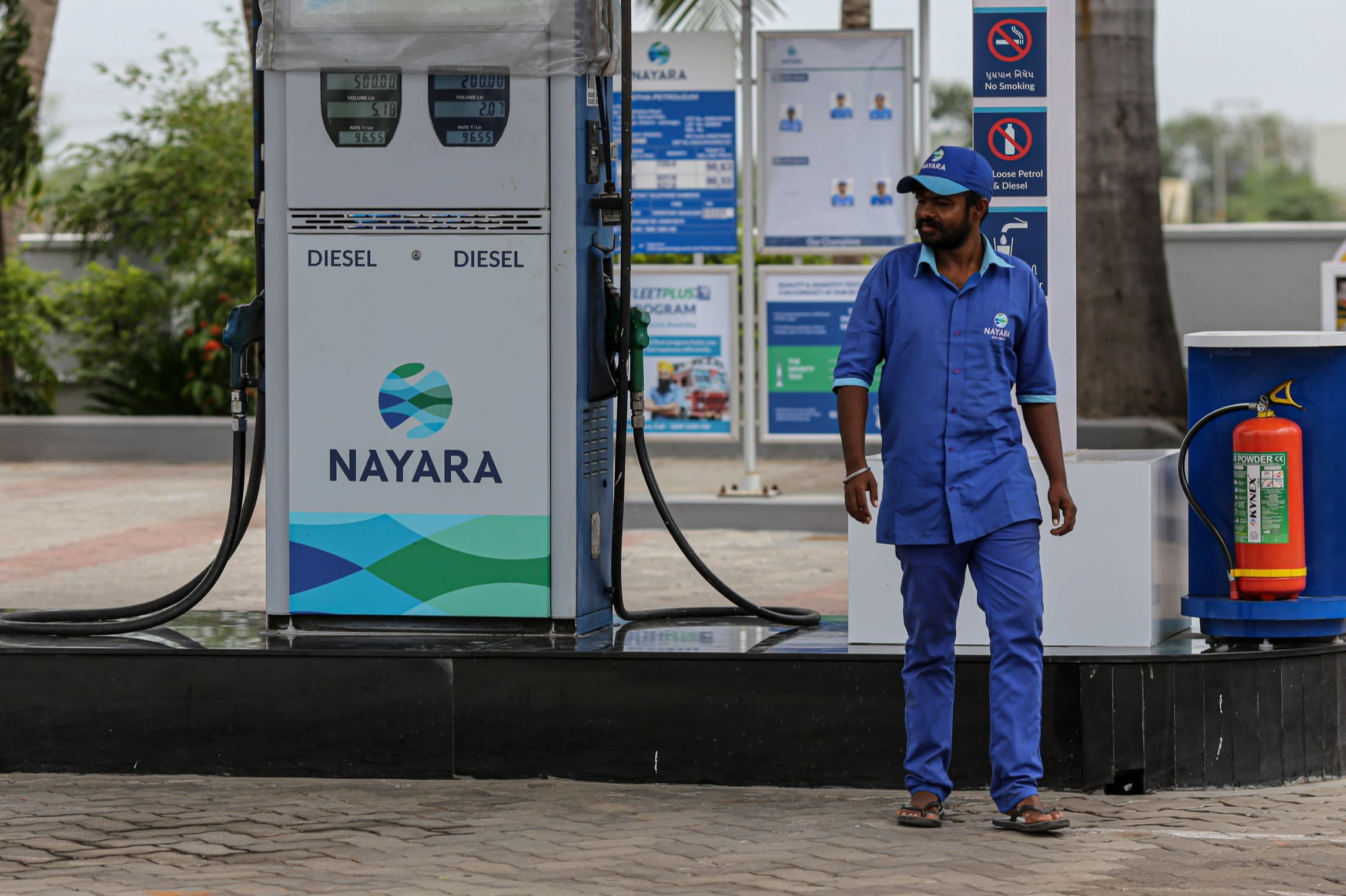 An Indian petrol station worker next to a pump