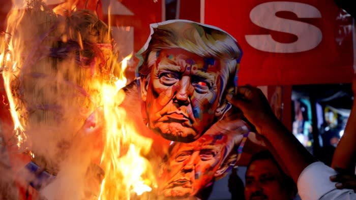 Political activists in Kolkata burn cardboard cutouts of Donald Trump during protests against US trade policies on India