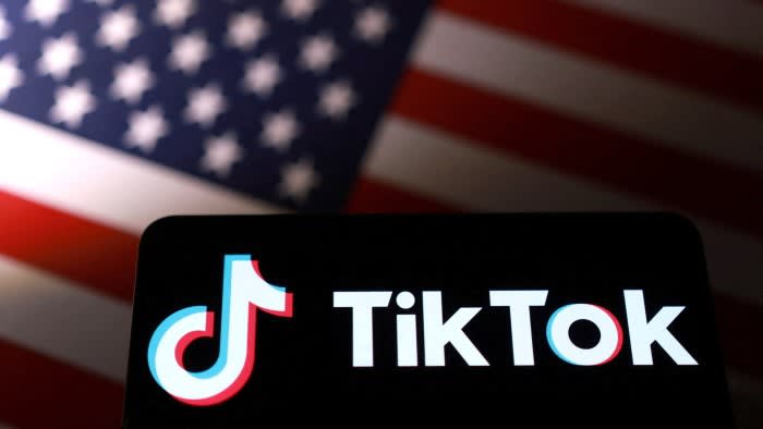 An illustration showing the TikTok logo on a screen with a blurred US flag in the background