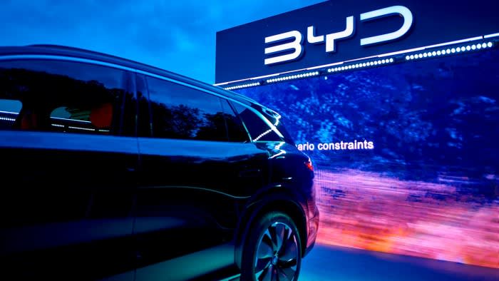 A BYD electric vehicle displayed in front of a large illuminated BYD sign at the IAA Mobility 2025 fair.