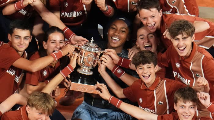 Coco Gauff poses with her trophy and ball boys