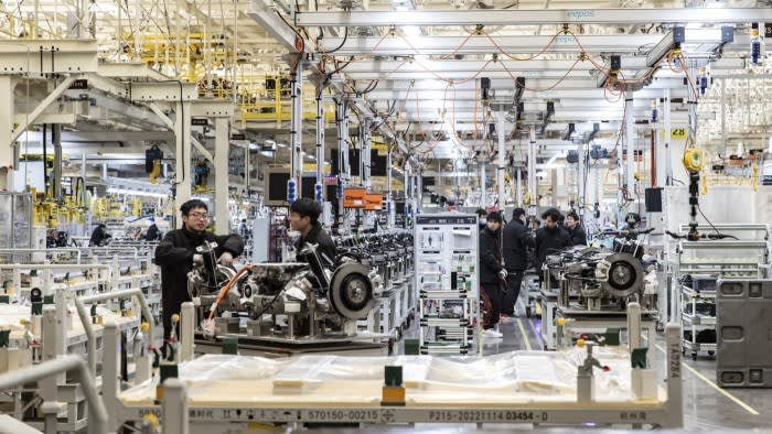 Workers assemble vehicle components on the production line at carmaker Zeekr’s factory, surrounded by machinery and equipment.