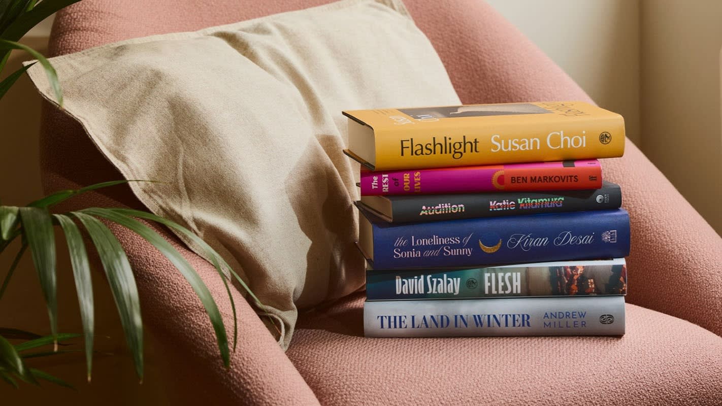 A stack of books on an armchair, with The Land in Winter by Andrew Miller; Flesh by David Szalay; The Loneliness of Sonia and Sunny by Kiran Desai; Audition by Katie Kitamura; The Rest of Our Lives by Ben Markovits; Flashlight by Susan Choi