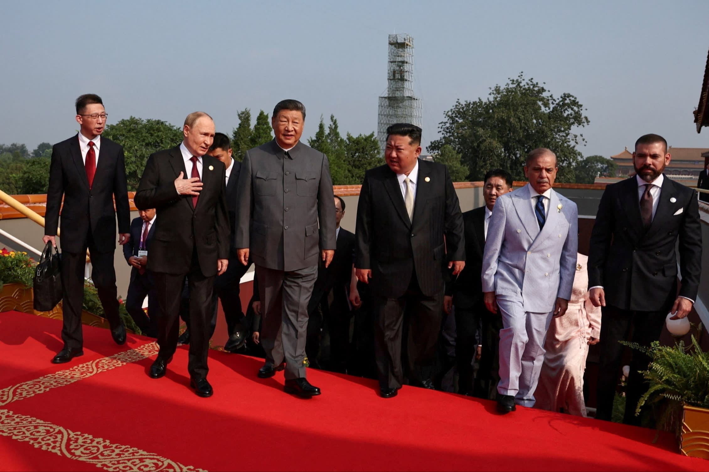 Vladimir Putin, Xi Jinping, Kim Jong Un, and Shehbaz Sharif walk together with other officials on a red carpet at the parade.