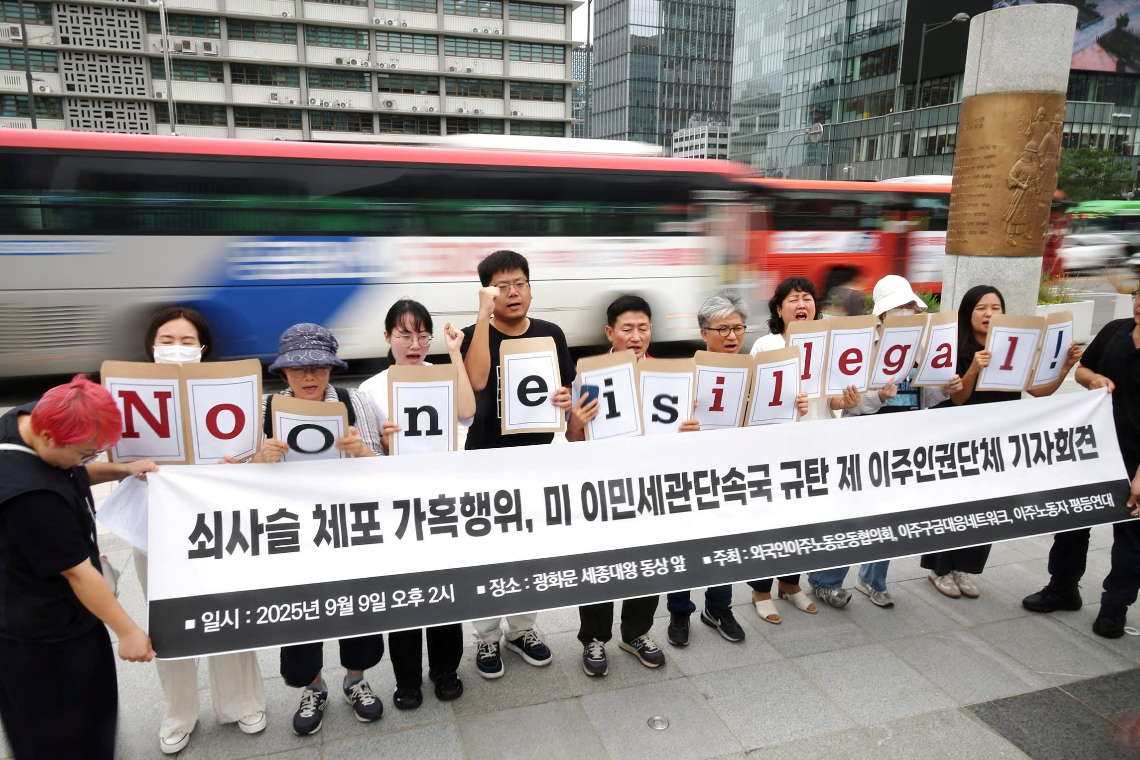 A group of activists in Seoul hold signs reading ‘No one is illegal!’ and chant during a protest against a US immigration raid