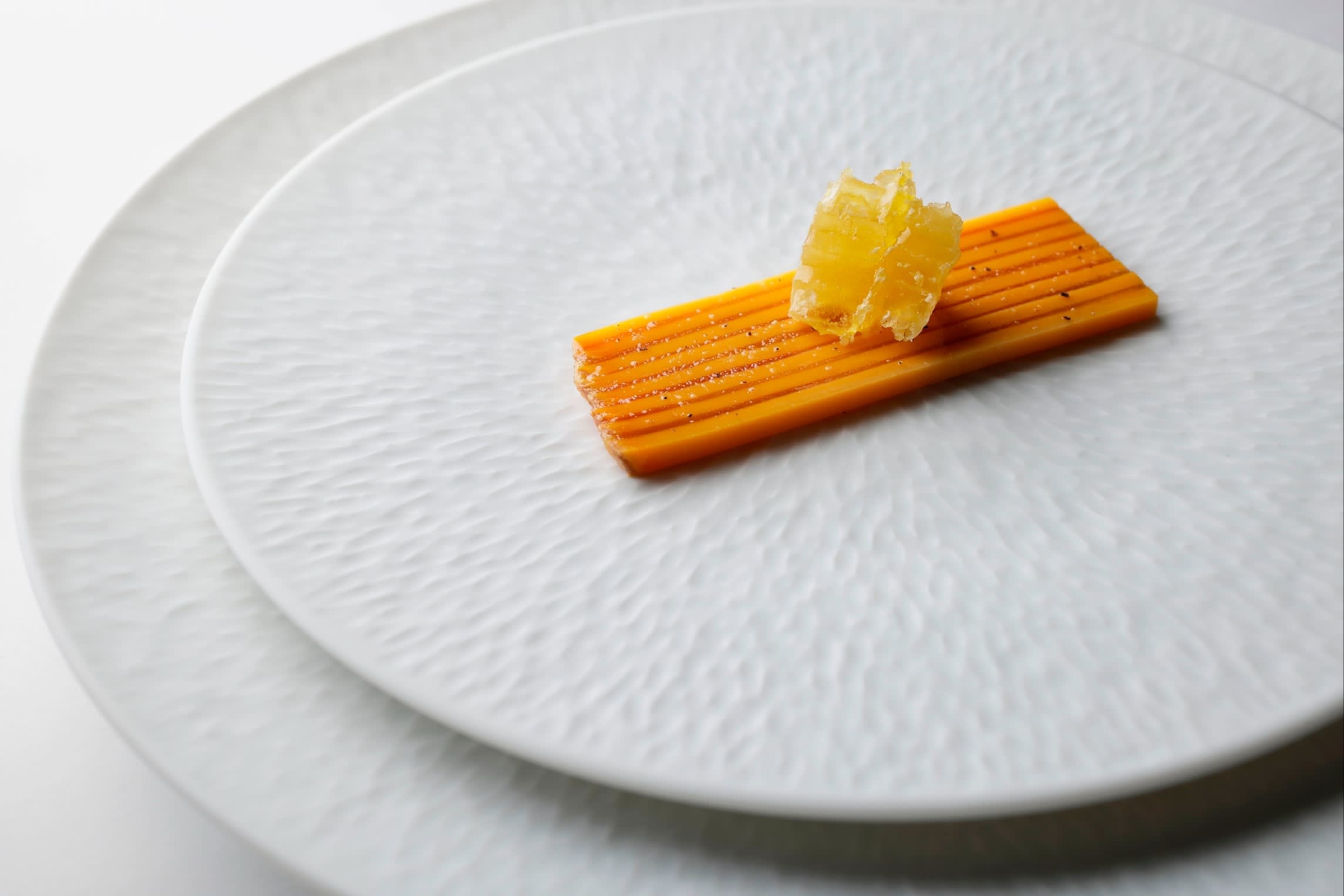 Mimolette karasumi — a piece of French cheese on top of two orange strips of cured mullet roe — at Sézanne