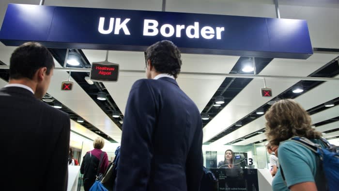 Travellers queue at the UK Border passport control in Terminal 2 at Heathrow airport, with an officer visible at the counter.