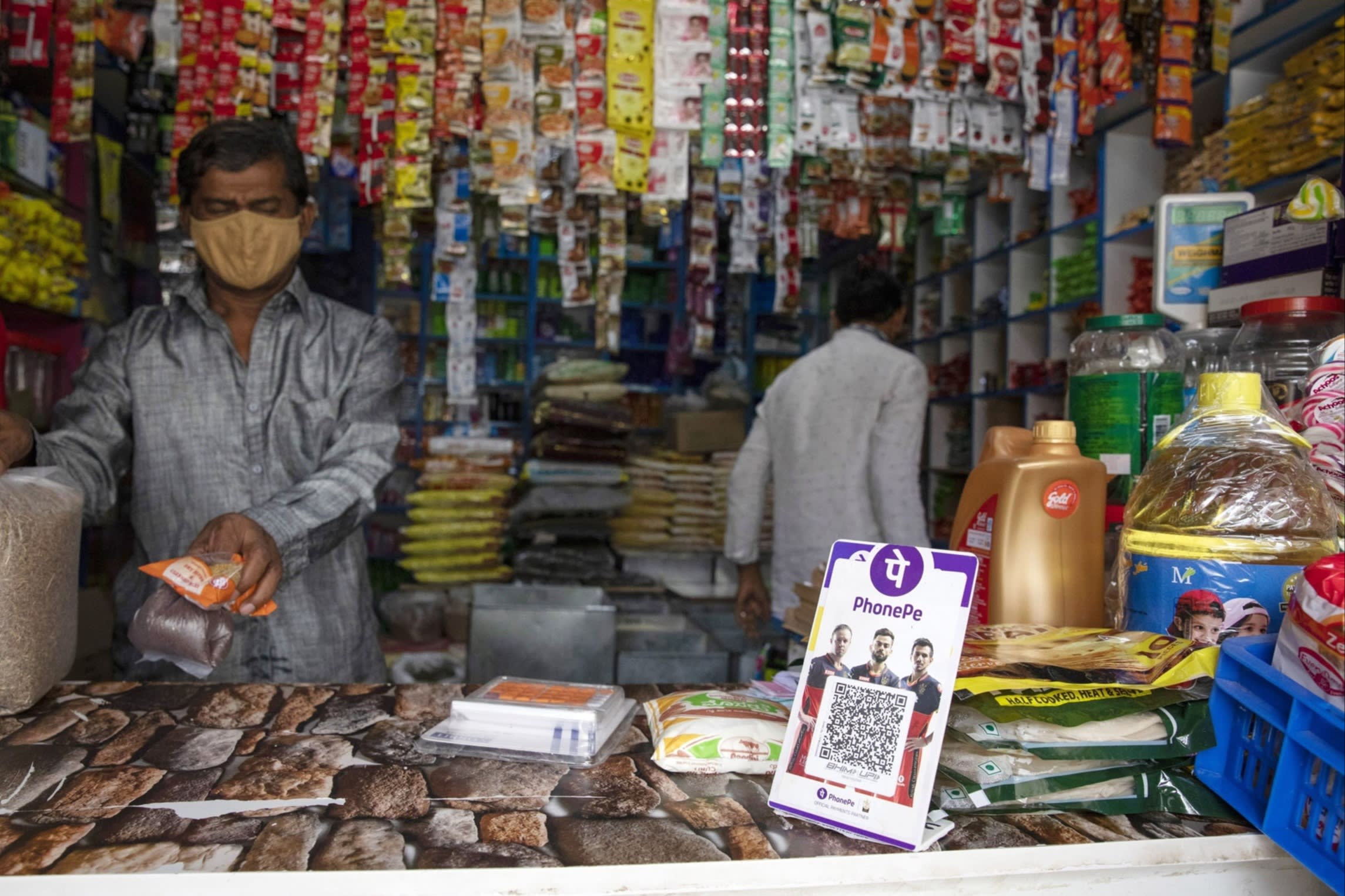 A grocery store counter displays a PhonePE QR code for digital payments.