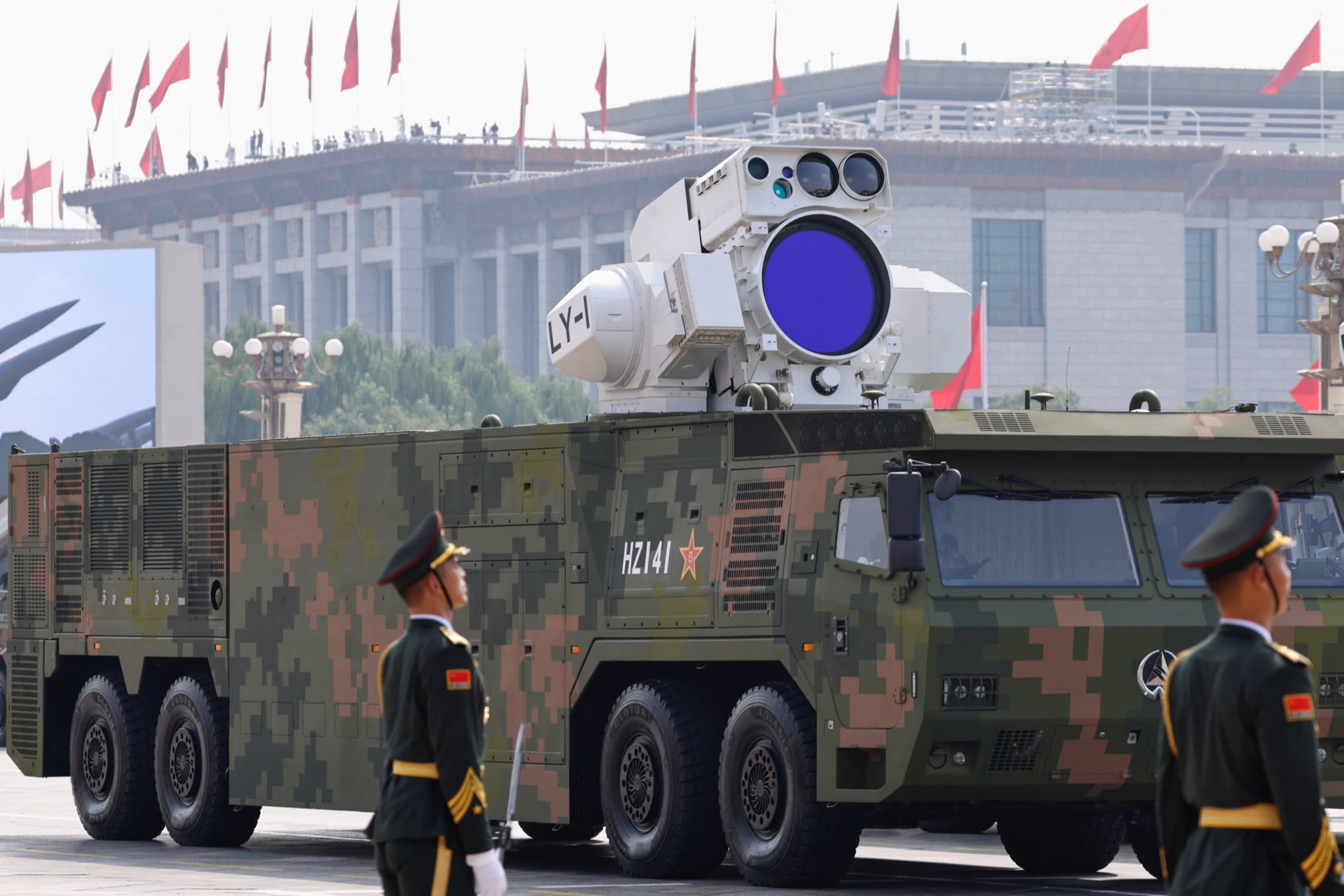 Members of the People's Liberation Army stand near a military vehicle displaying an air-defence laser weapon during a parade.